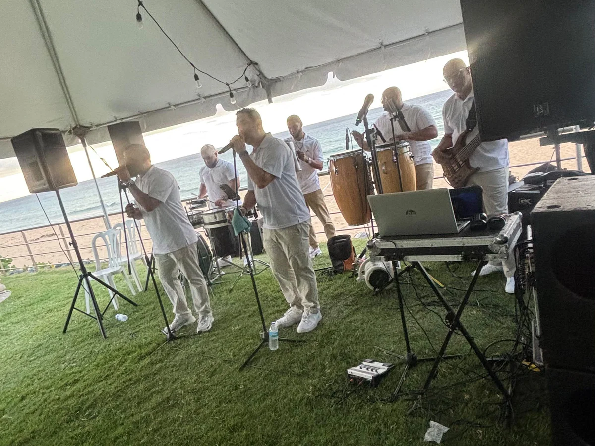 Grupo musical presentándose bajo una carpa frente al mar