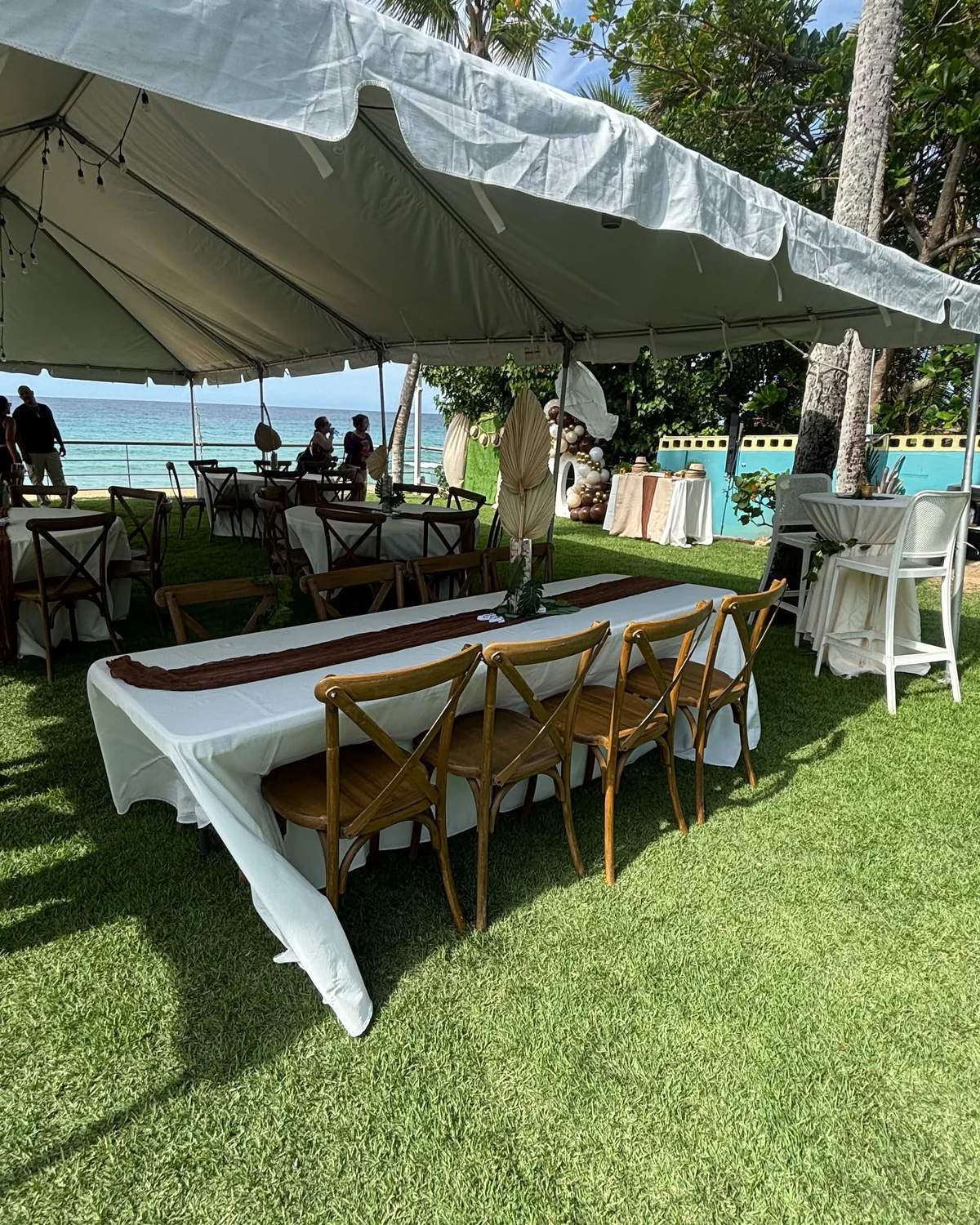 Mesas y sillas preparadas bajo una carpa blanca frente al mar